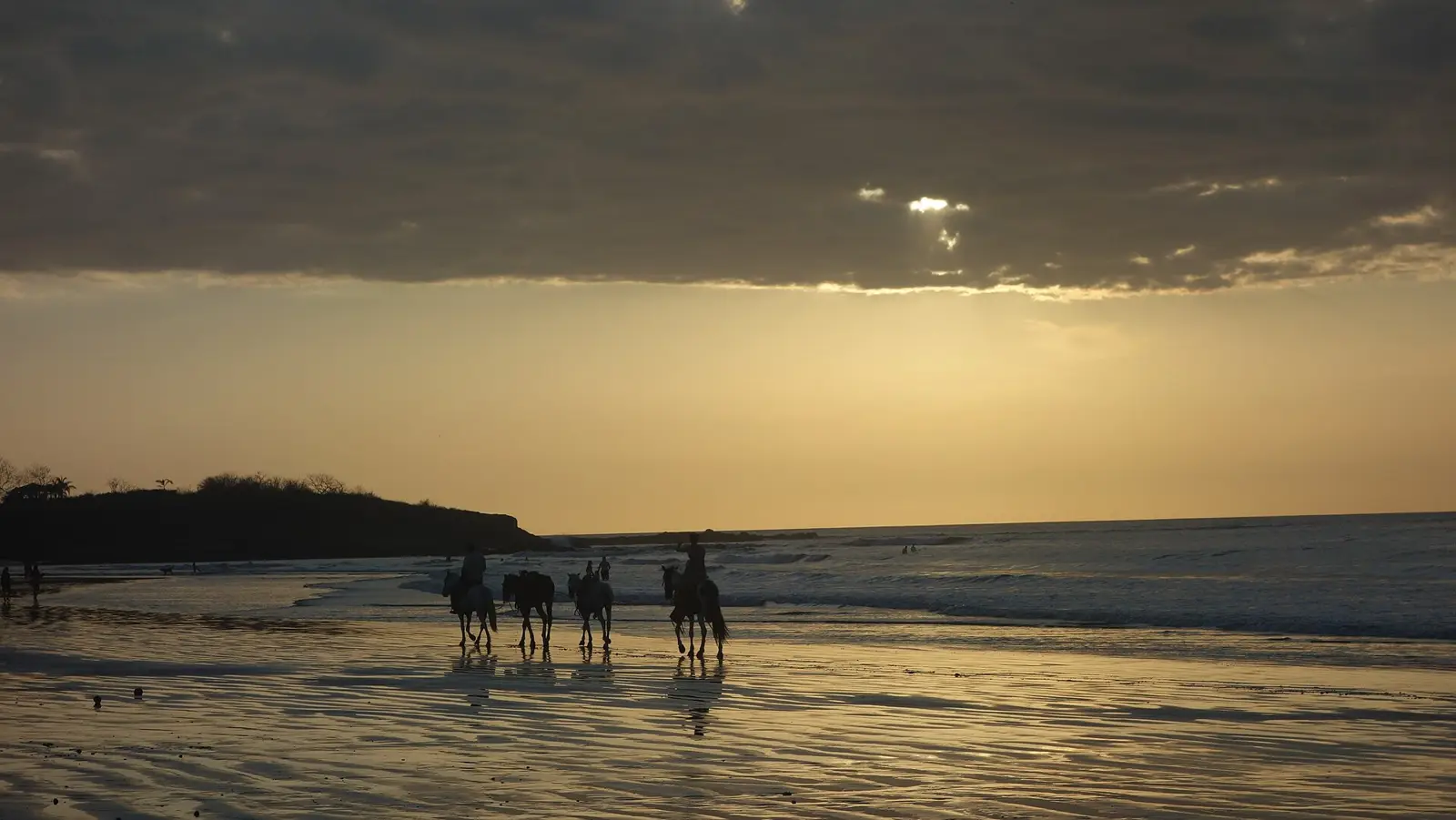 Horseback riders on Playa Tamarindo at sunset